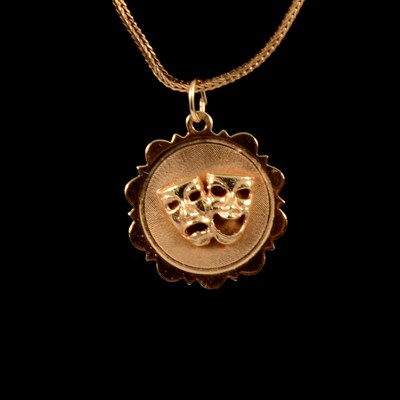 Lot 242 - A comedy and tragedy mask pendant on a 9 carat gold foxtail link chain.