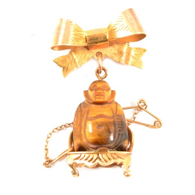 Lot 289 - A tigers eye Buddha pendant suspended from a bow brooch.