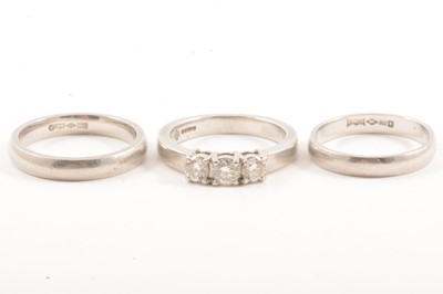 Lot 9 - A diamond three stone ring and two platinum wedding bands.