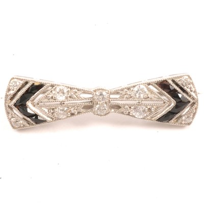 Lot 253 - Tiffany & Co - a diamond and black onyx bow brooch.