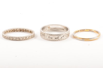 Lot 107A - A platinum wedding band, eternity ring and platinum and gold band.