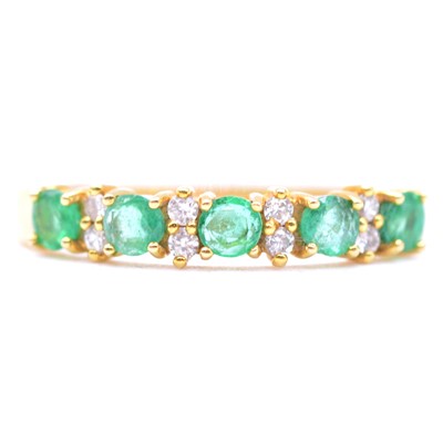 Lot 37 - An emerald and diamond half eternity ring.