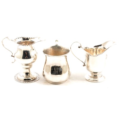 Lot 257 - Two silver cream jugs and a christening mug.