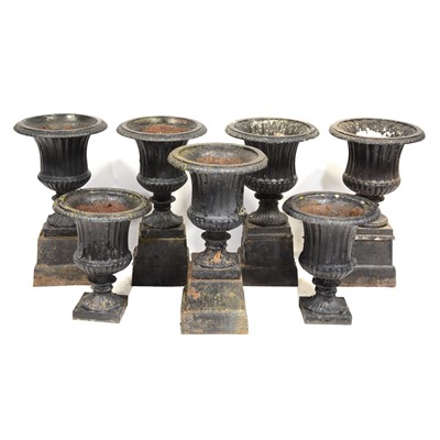 Lot 638 - Set of five Victorian cast iron garden urns, on plinths, and another pair of urns