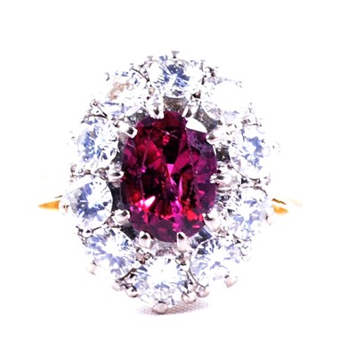 Lot 37 - A ruby and diamond oval cluster ring.