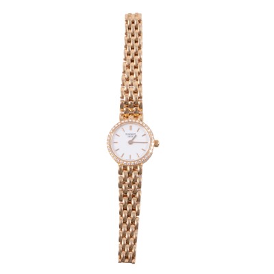 Lot 397 - Tissot - a lady's 18 carat yellow gold bracelet wristwatch with diamond set bezel.